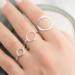 Hand with three open circle sterling silver rings (small, medium, large with hammered finish) on soft background.

